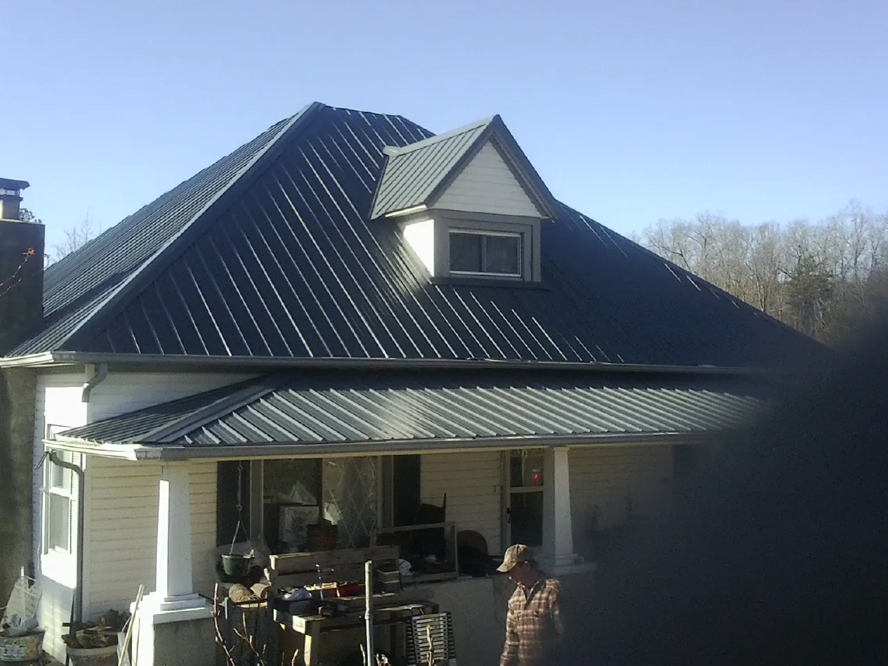 Dark blue standing seam metal roof with a dormer above a front porch in North Washington