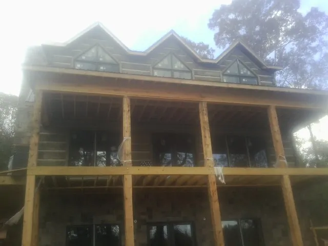 Dormers and porch framing on a large log home under construction — Roof Coating work by our crew in North Washington