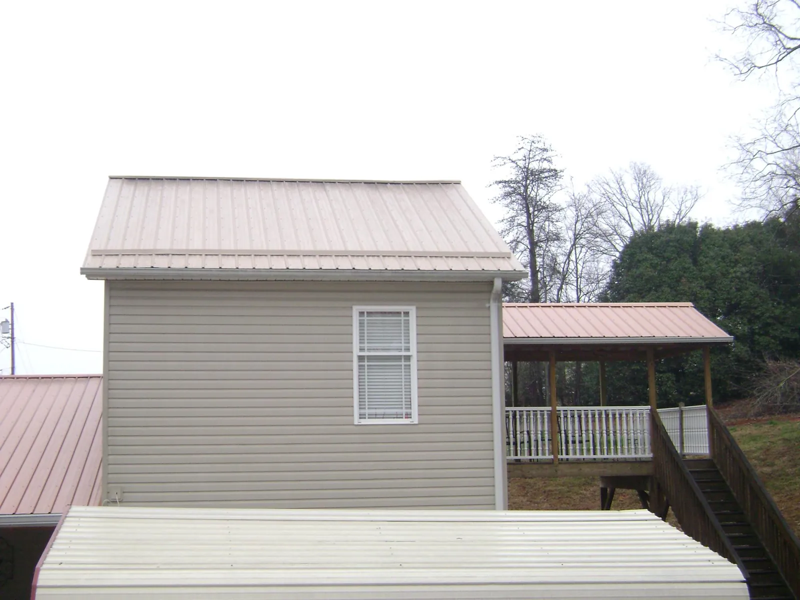 Tan metal roofs on a two story addition and attached porch, from a Roof Replacement job in North Washington