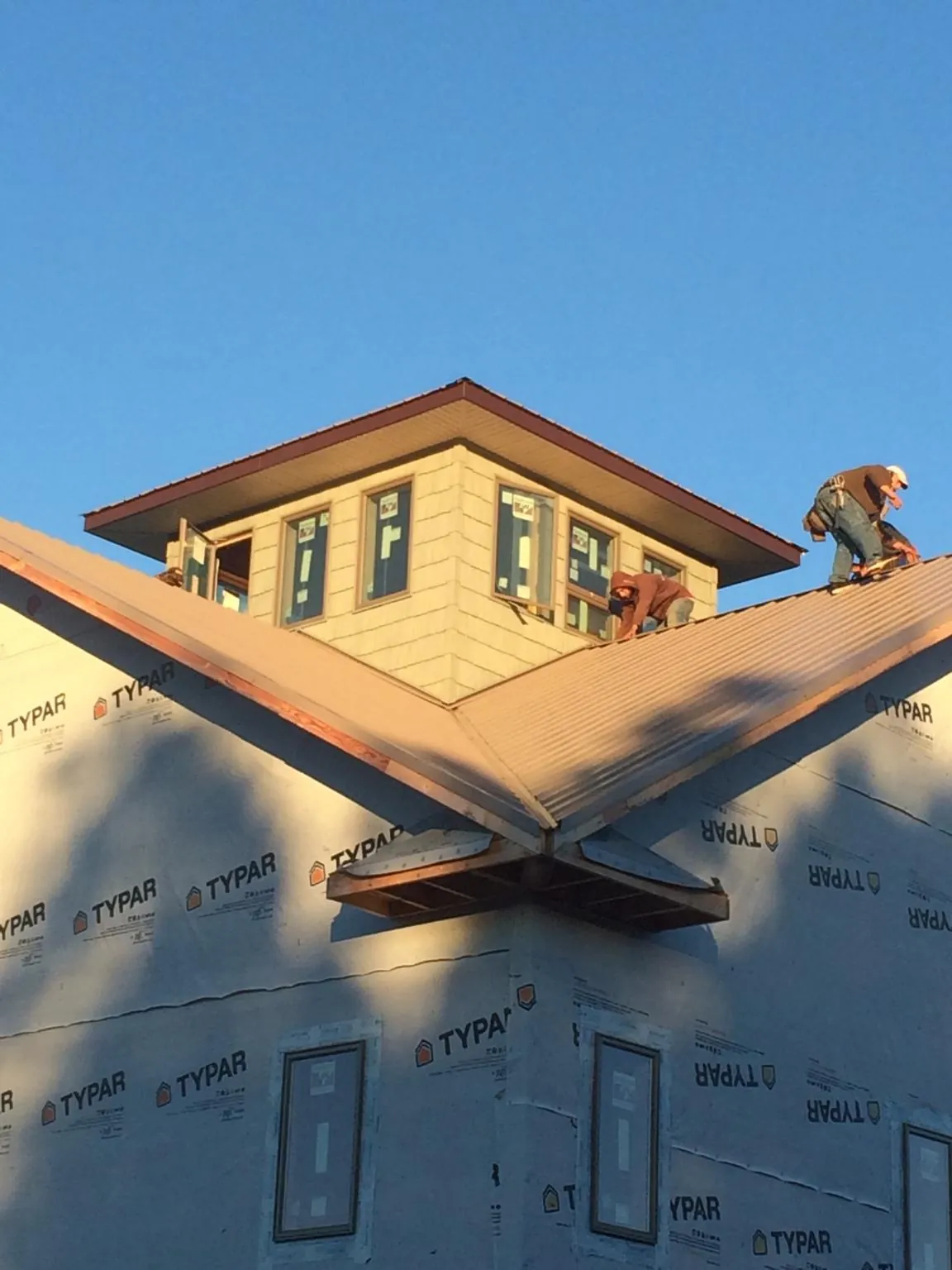 Roofers working around a rooftop cupola on a new metal roof at sunset — Roof Waterproofing in North Washington by Roofing Brothers